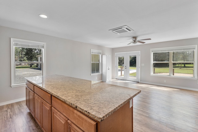 kitchen with a kitchen island, ceiling fan, french doors, and light hardwood / wood-style floors