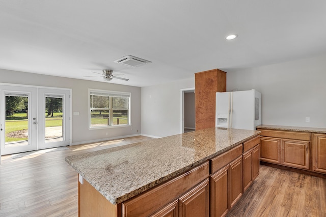 kitchen with plenty of natural light, light hardwood / wood-style floors, white refrigerator with ice dispenser, ceiling fan, and a kitchen island