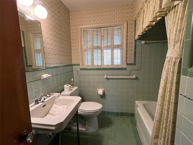 full bathroom with shower / tub combo with curtain, tasteful backsplash, tile patterned flooring, tile walls, and toilet