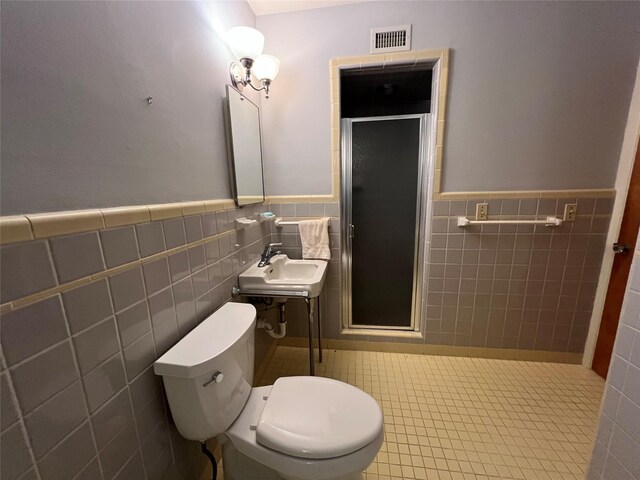 bathroom with an enclosed shower, tasteful backsplash, tile walls, toilet, and sink