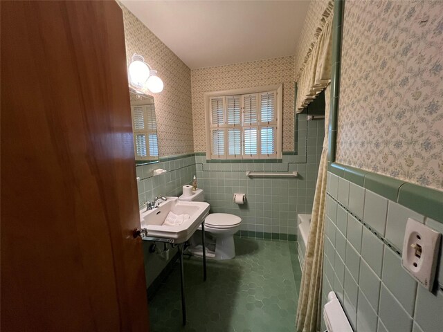 bathroom featuring tile walls, toilet, sink, and a washtub