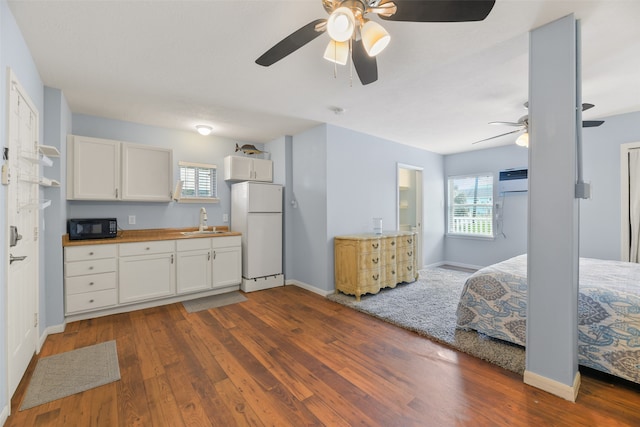 kitchen featuring white refrigerator, ceiling fan, dark hardwood / wood-style floors, and white cabinets