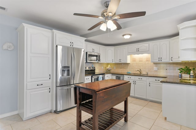 kitchen featuring light tile patterned floors, stainless steel appliances, ceiling fan, decorative backsplash, and white cabinets