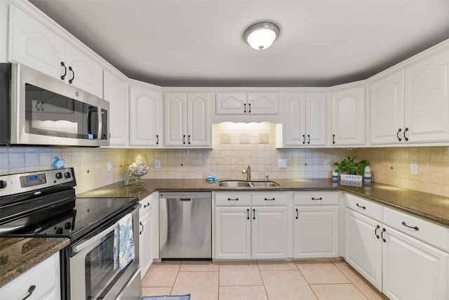 kitchen featuring white cabinets, dark stone countertops, stainless steel appliances, and sink