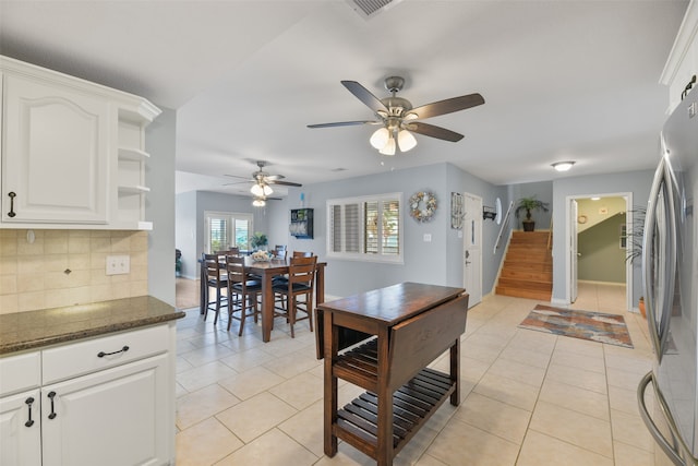 kitchen with dark stone countertops, white cabinetry, tasteful backsplash, light tile patterned floors, and ceiling fan