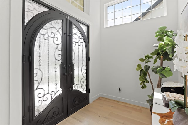 foyer entrance with french doors and light hardwood / wood-style flooring