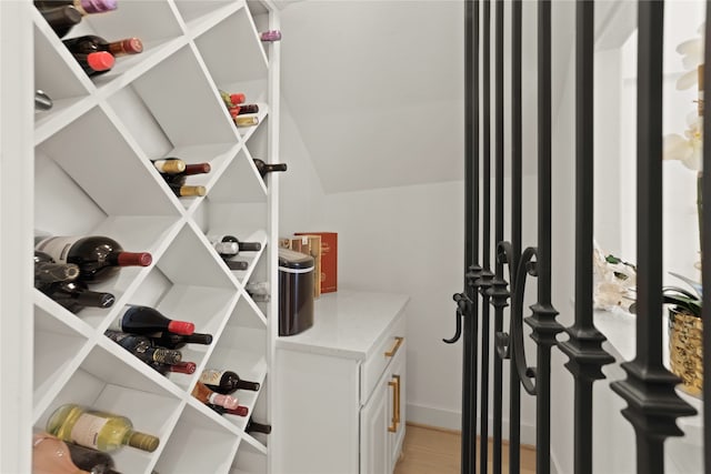 wine area with light hardwood / wood-style floors and lofted ceiling