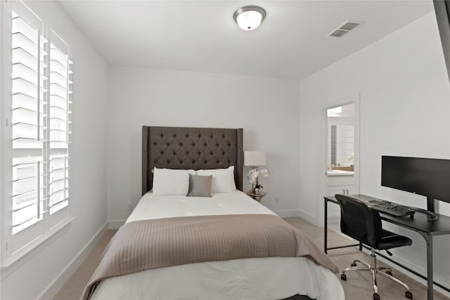 bedroom with ensuite bathroom and carpet flooring