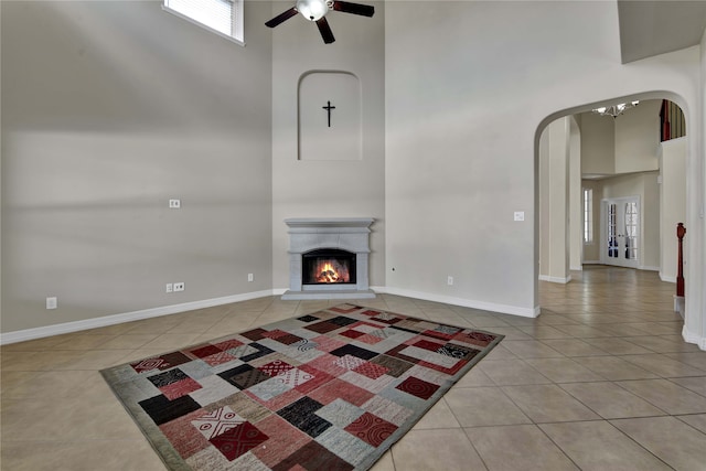 unfurnished living room featuring light tile patterned floors, a high ceiling, and ceiling fan