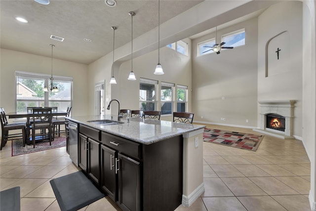 kitchen with ceiling fan with notable chandelier, an island with sink, pendant lighting, and sink