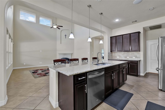 kitchen with a kitchen island with sink, sink, stainless steel appliances, dark brown cabinetry, and ceiling fan