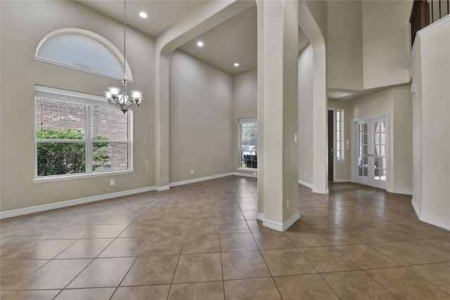 interior space featuring an inviting chandelier, light tile patterned flooring, and a towering ceiling