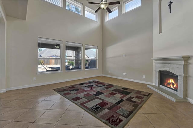 unfurnished living room featuring ceiling fan, light tile patterned flooring, and a towering ceiling