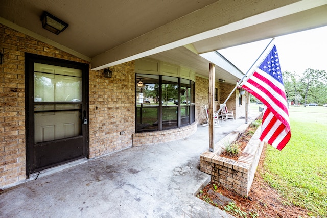 view of exterior entry with a yard and a patio area