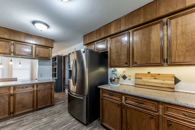 kitchen featuring a textured ceiling, dark wood-type flooring, tasteful backsplash, and stainless steel refrigerator with ice dispenser