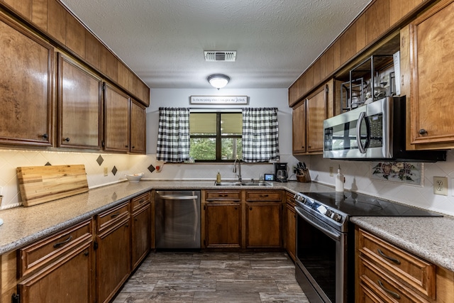 kitchen with a textured ceiling, tasteful backsplash, sink, dark hardwood / wood-style floors, and appliances with stainless steel finishes