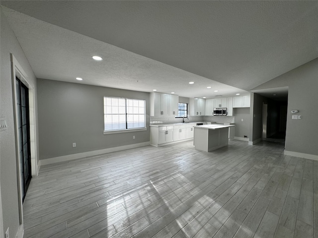 unfurnished living room with a textured ceiling, light hardwood / wood-style floors, and sink