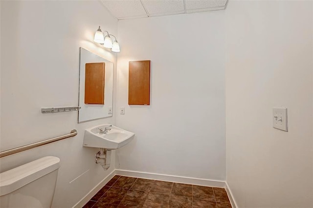 9788 Clarewood Dr Unit 201, Houston, TX 77036 - bathroom with baseboards, toilet, a drop ceiling, and a sink