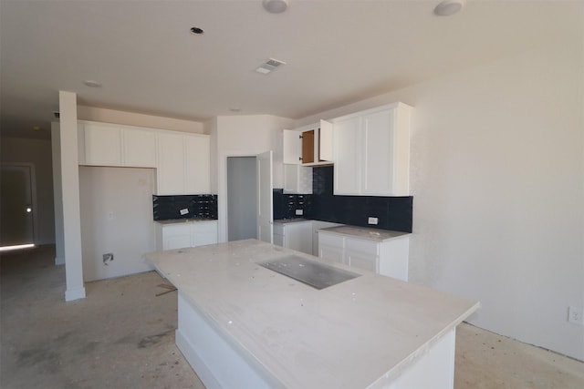 kitchen featuring a center island, decorative backsplash, and white cabinets