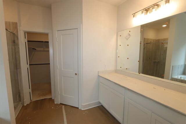 full bathroom with vanity, baseboards, a spacious closet, a stall shower, and a bathtub