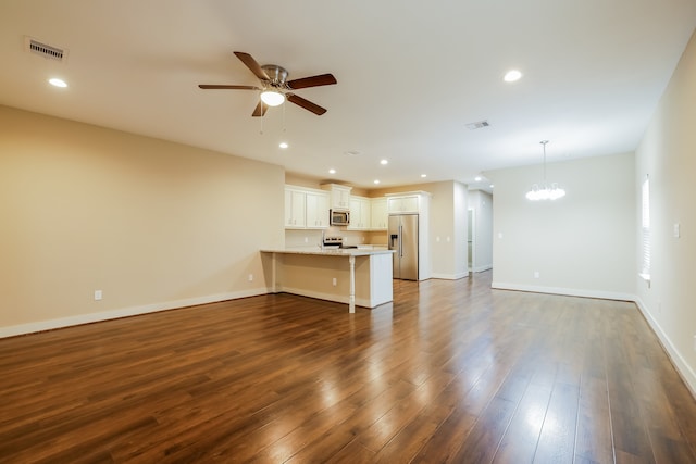 unfurnished living room featuring ceiling fan with notable chandelier and dark hardwood / wood-style floors