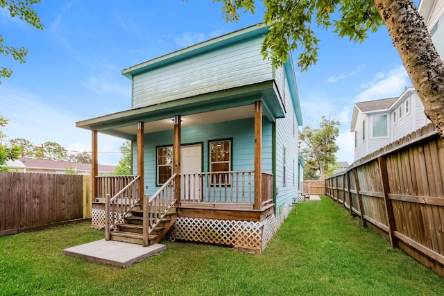 back of property with a lawn and a porch