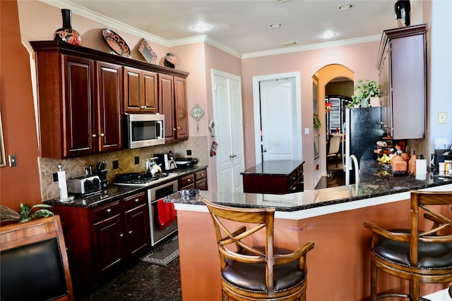 kitchen with a kitchen island, stainless steel appliances, ornamental molding, and a breakfast bar