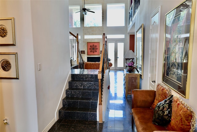 staircase featuring a towering ceiling and ceiling fan