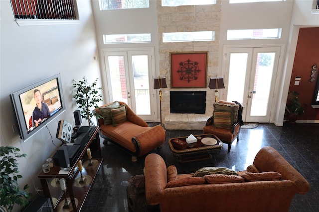 living room with a towering ceiling, french doors, and a stone fireplace