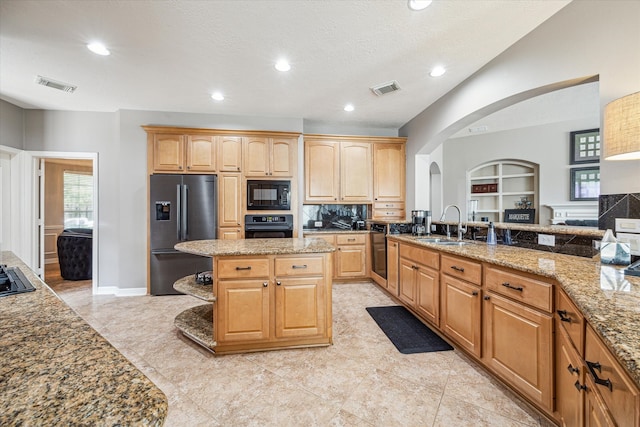 kitchen with light stone countertops, sink, black appliances, a kitchen island, and a textured ceiling