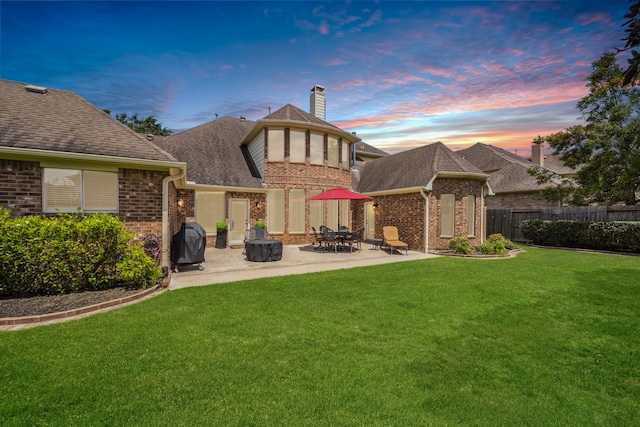 back house at dusk with a yard, a patio area, and a fire pit