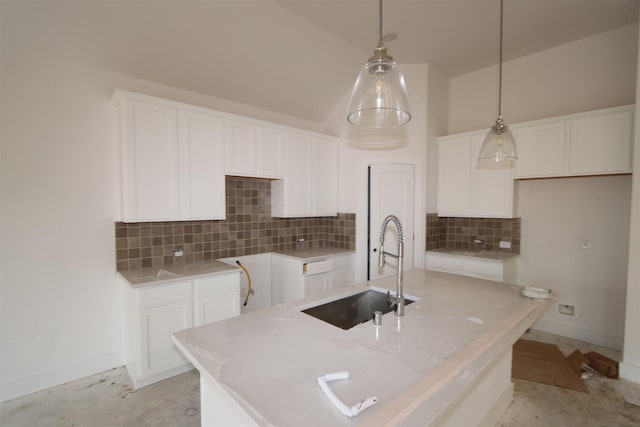 kitchen with backsplash, a center island with sink, sink, white cabinetry, and hanging light fixtures