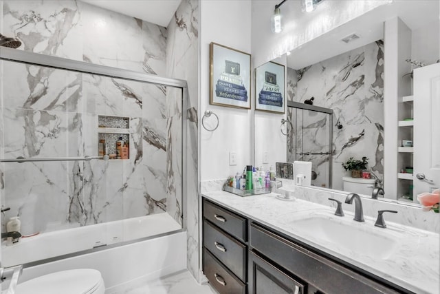 full bathroom featuring vanity, toilet, and combined bath / shower with glass door