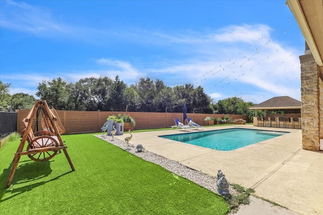 view of swimming pool with exterior bar, a patio area, and a lawn