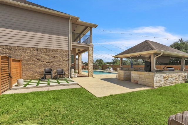 exterior space with a lawn, an outdoor bar, a swimming pool, a patio area, and an outdoor kitchen