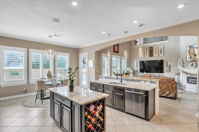 kitchen with dishwasher, sink, hanging light fixtures, a kitchen island with sink, and light stone countertops