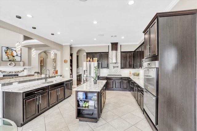 kitchen with sink, decorative light fixtures, dark brown cabinets, appliances with stainless steel finishes, and an island with sink