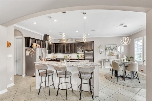 kitchen featuring a large island, hanging light fixtures, a kitchen breakfast bar, stainless steel appliances, and dark brown cabinetry