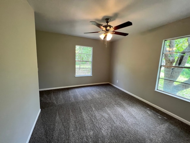 empty room with dark carpet, ceiling fan, and plenty of natural light