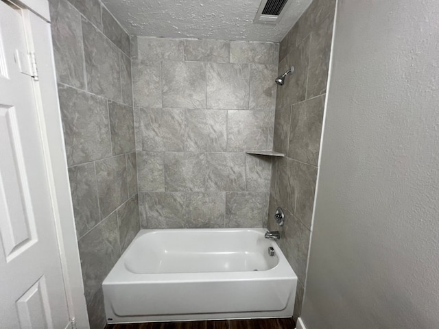 bathroom with tiled shower / bath and a textured ceiling