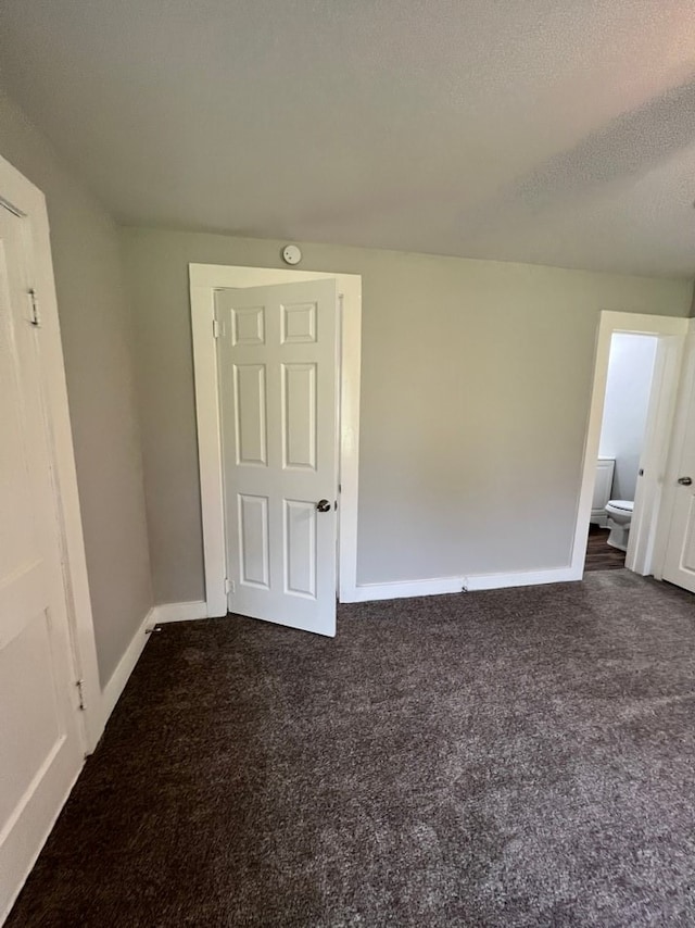 unfurnished room with dark carpet and a textured ceiling