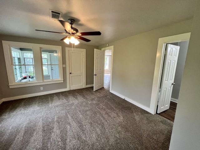 unfurnished bedroom with dark colored carpet and ceiling fan