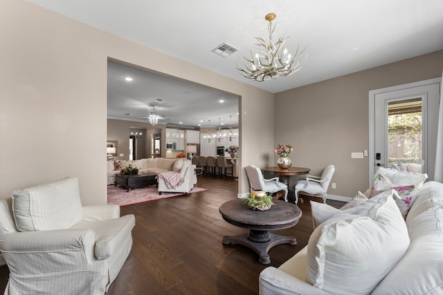 living room with ceiling fan with notable chandelier and dark hardwood / wood-style flooring