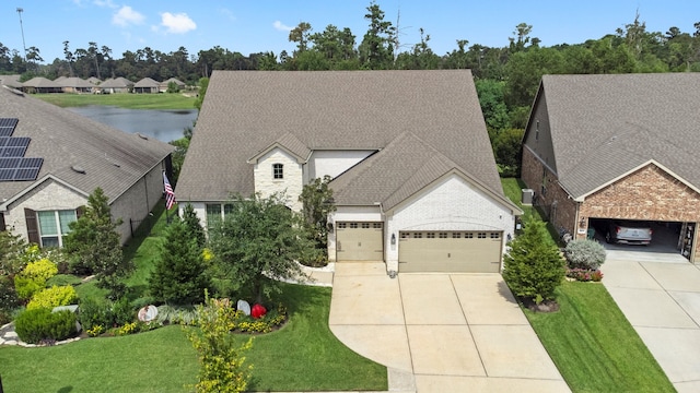 view of front of home with a water view, a garage, and a front lawn