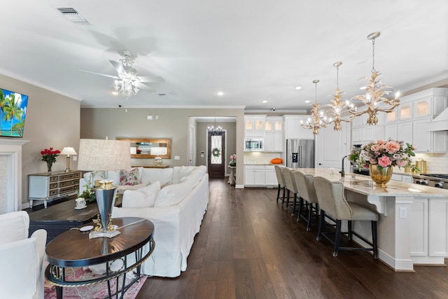 living room featuring ceiling fan with notable chandelier, crown molding, and dark hardwood / wood-style flooring