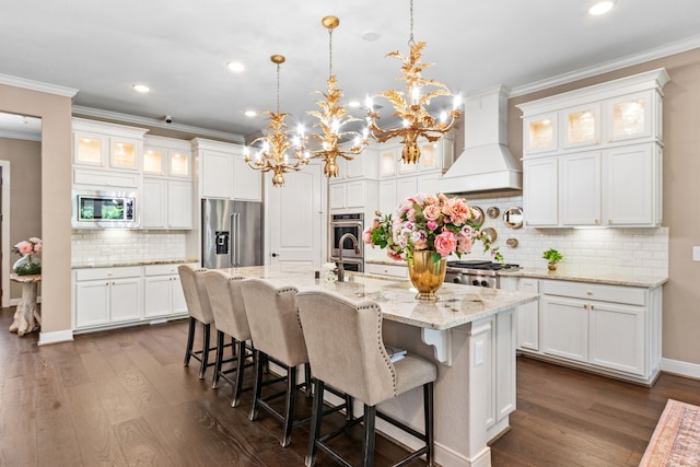 kitchen with appliances with stainless steel finishes, custom range hood, a chandelier, and white cabinets