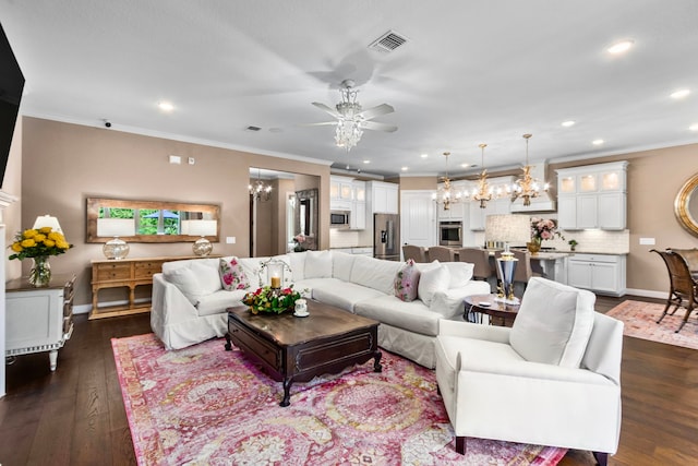 living room with ceiling fan with notable chandelier, ornamental molding, and dark wood-type flooring