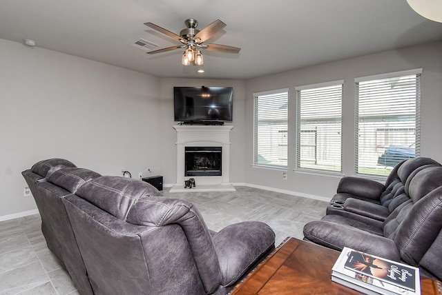 living room with a ceiling fan, baseboards, visible vents, and a fireplace with raised hearth