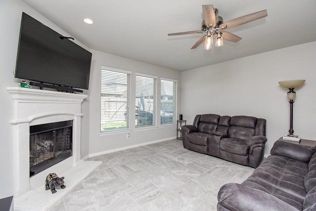 living room with baseboards, a ceiling fan, a fireplace with raised hearth, and recessed lighting