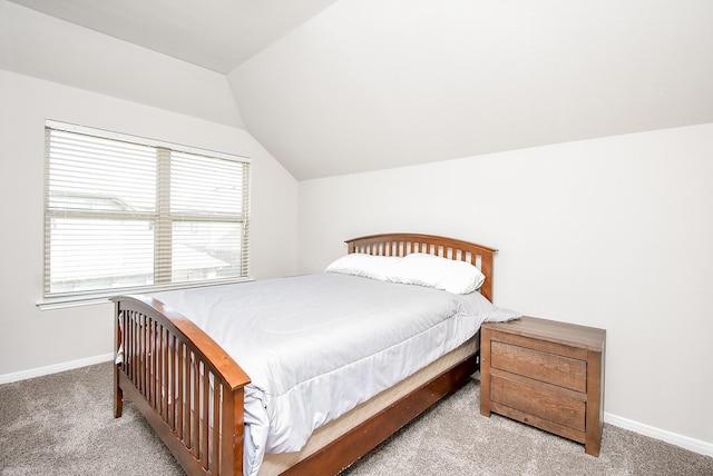 carpeted bedroom featuring baseboards and lofted ceiling